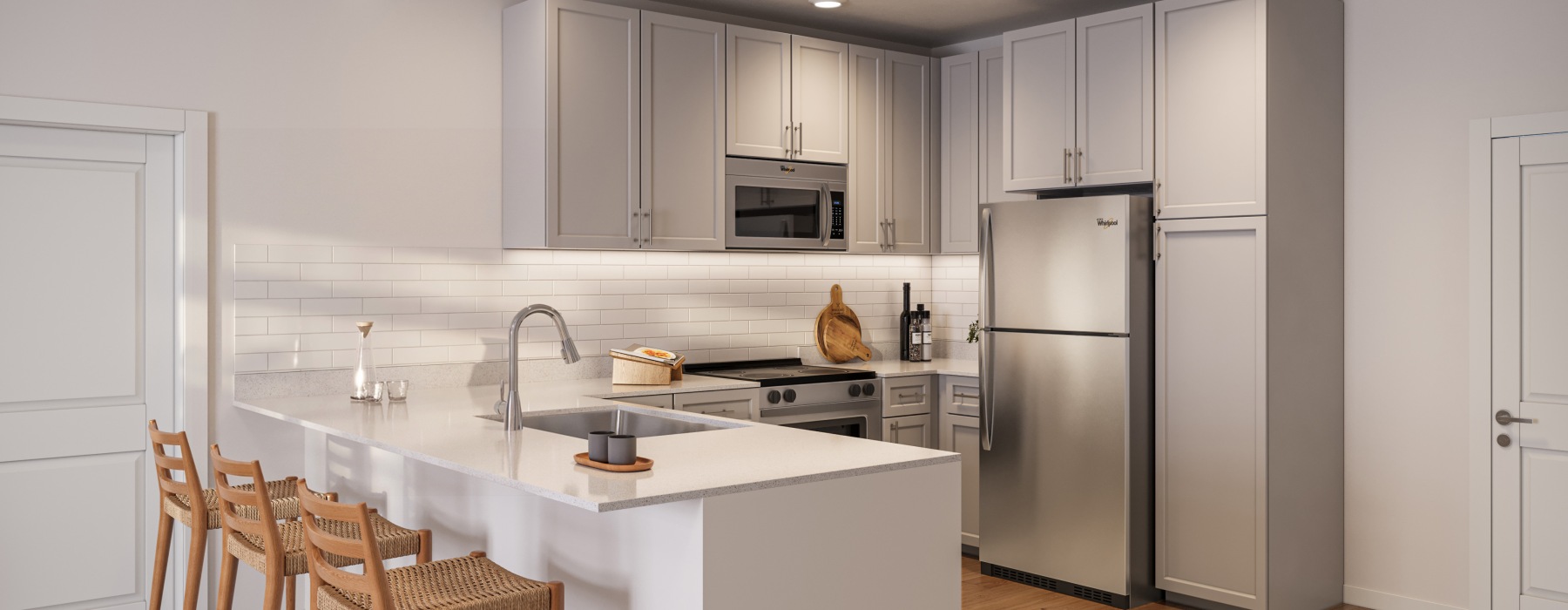 Kitchen fully equipt with stainless steel applicances, quartz countertops, tile backsplash, countertop bar, and wood like flooring for a modern feel. 