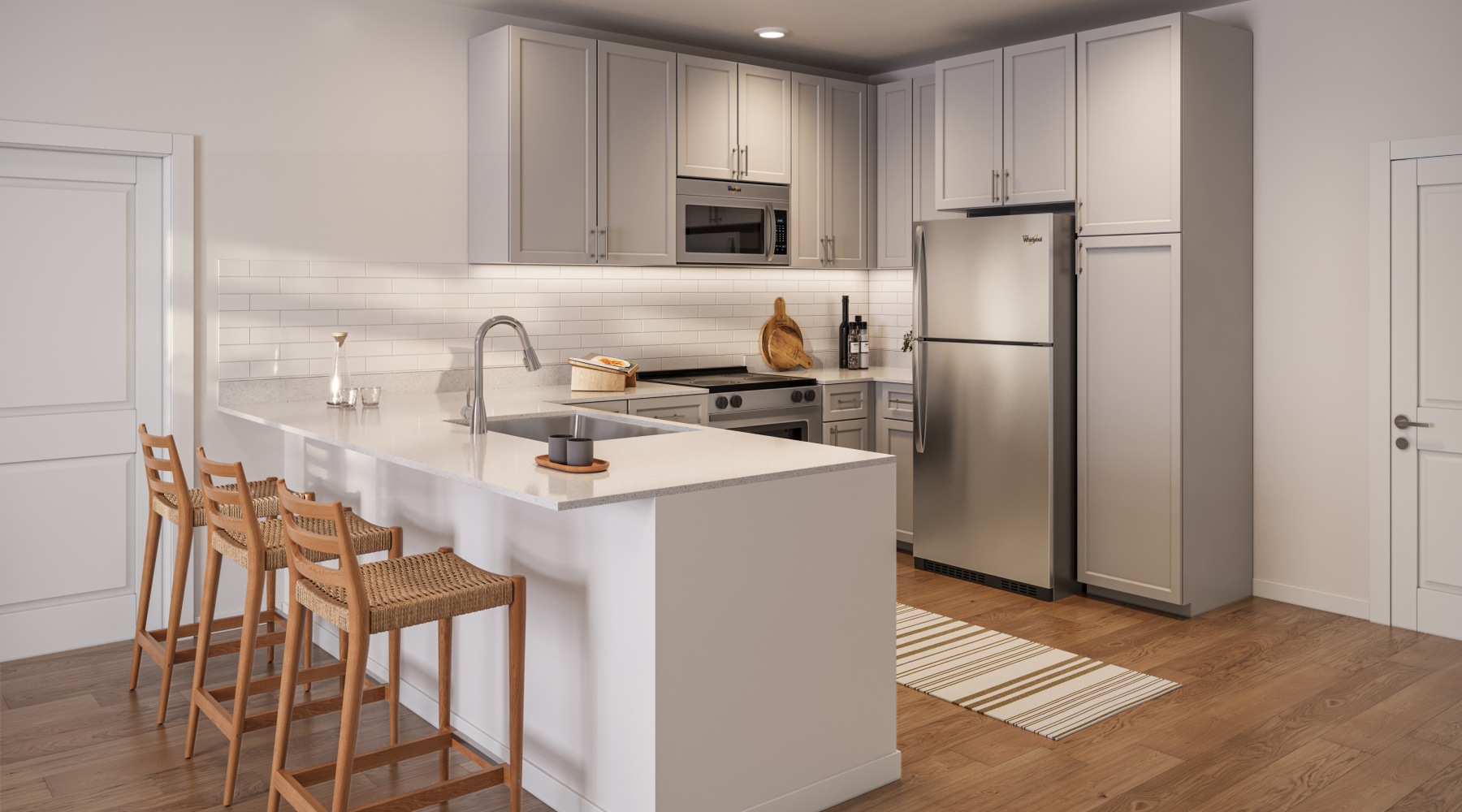Kitchen fully equipt with stainless steel applicances, quartz countertops, tile backsplash, countertop bar, and wood like flooring for a modern feel. 