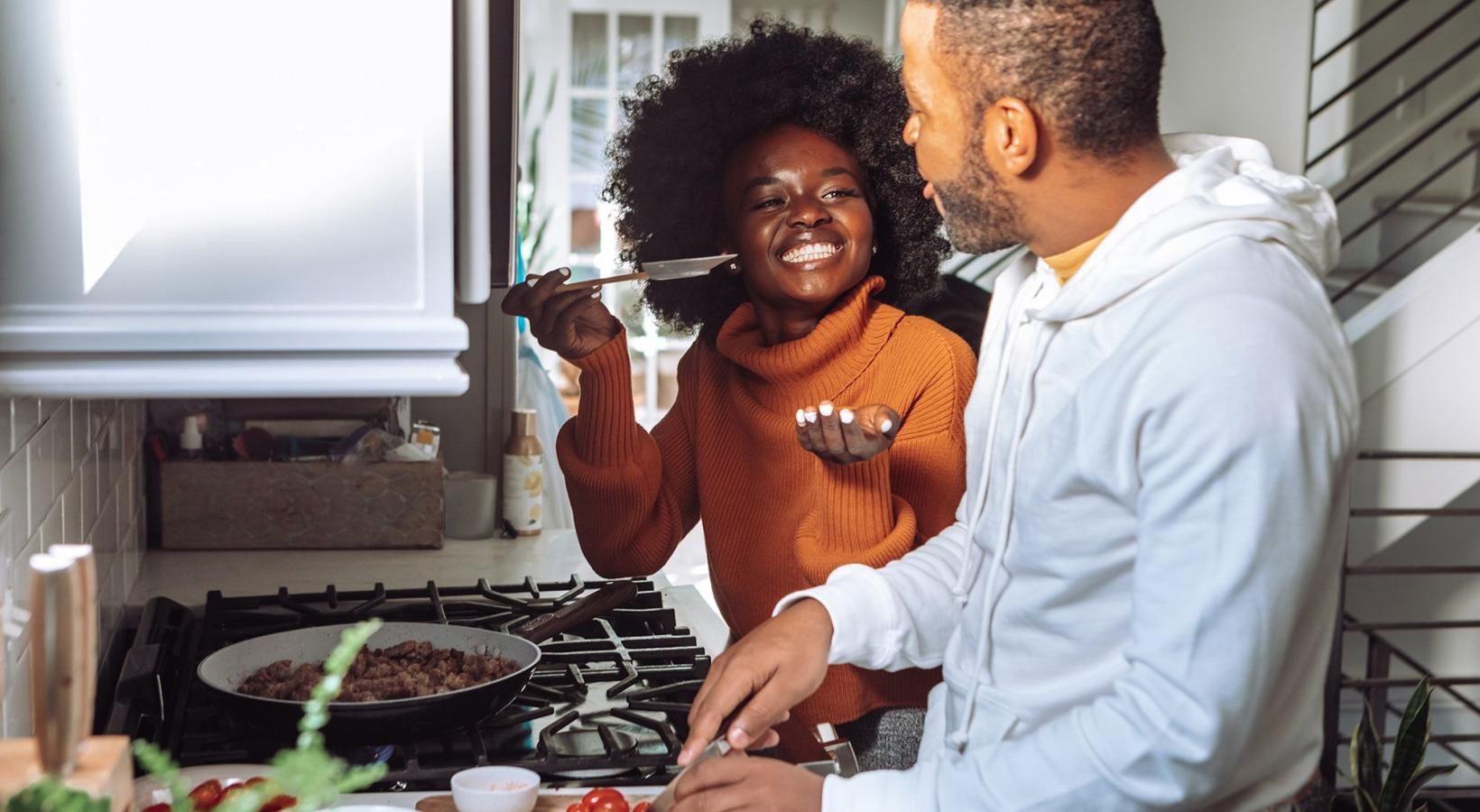 a man and a woman cooking on a gas stove top